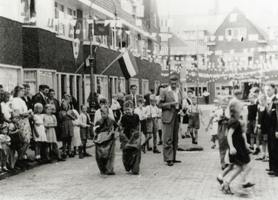 109230 Afbeelding van deelnemers aan een buurtfeest in de versierde Walnootstraat te Utrecht; in het midden twee ...